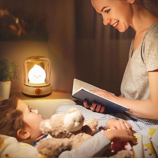 Mère lisant un livre à son enfant, éclairée par une veilleuse bébé en forme de chandelle