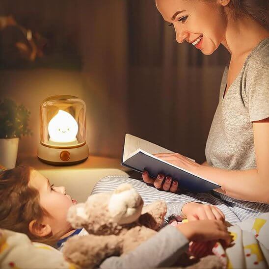 Mère lisant un livre à son enfant, éclairée par une veilleuse bébé en forme de chandelle