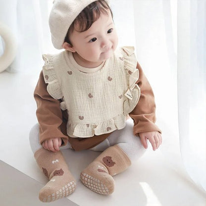 Bavoir bébé coton brodé sur un enfant assis, avec un style doux et élégant.