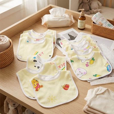 Bavoir bébé coton ultra-absorbant à poche brodé, ensemble coloré sur une table en bois.