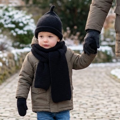 Bonnet bebe noir porté par un enfant, tenant la main d'un adulte sur un chemin en hiver.