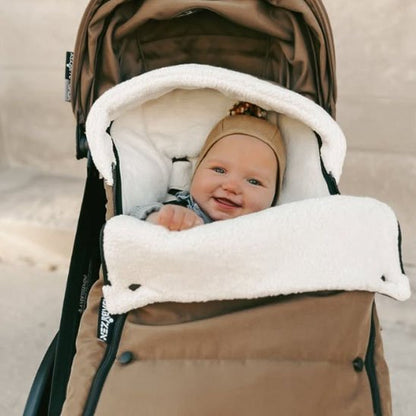Chanceliere poussette ultra-confortable avec bébé souriant à l'intérieur, parfait pour les balades hivernales.