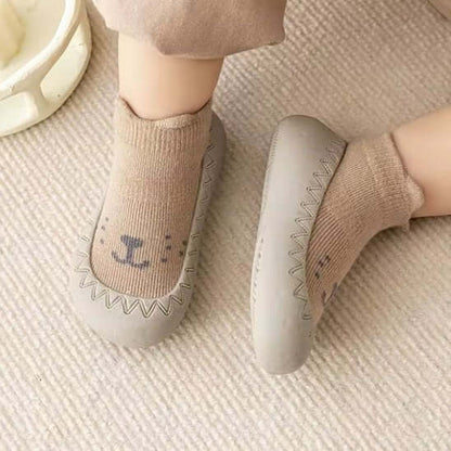 Chaussure bebe de couleur grise avec chaussettes beiges, conçues pour le confort des premiers pas.