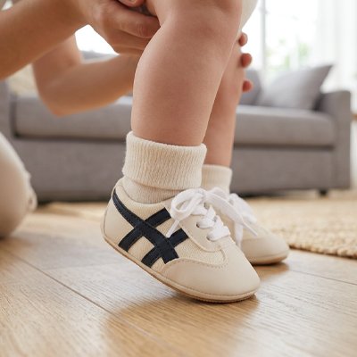 Chaussure bebe : des chaussures pour les premiers pas confortables et stylées sur un sol en bois.