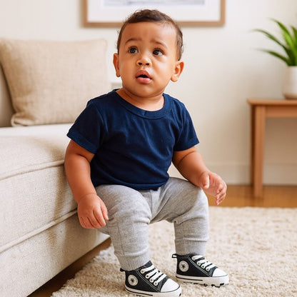 Bébé assis sur un canapé, portant une t-shirt bleu et des chaussure bebe Converse, prêt pour ses premiers pas.