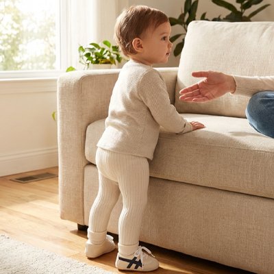 Chaussure bebe, un enfant debout près d'un canapé, prêt à faire ses premiers pas avec confiance.