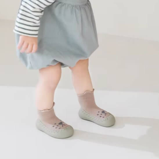 Chaussure bebe confortable pour les premiers pas d'un bébé, avec des chaussettes mignonnes et un vêtement léger.
