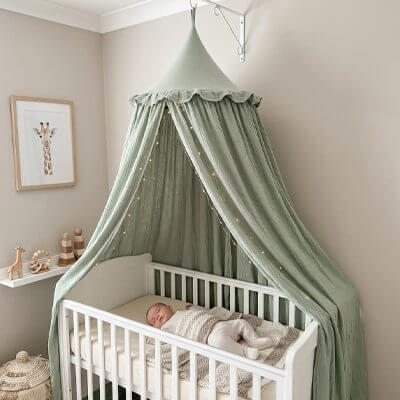Ciel de lit bébé en tissu vert dans la chambre d'un nourrisson endormi.