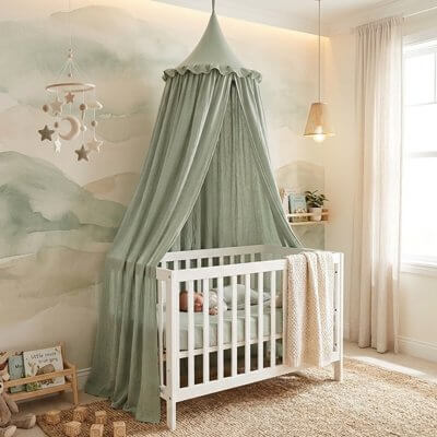 Ciel de lit bébé en tissu vert dans la chambre d'un bébé avec un berceau blanc.