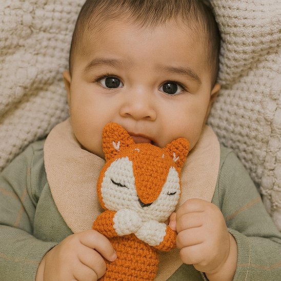 Doudou bebe tenant un doudou en forme de renard, jouet doux pour réconfort et câlins.
