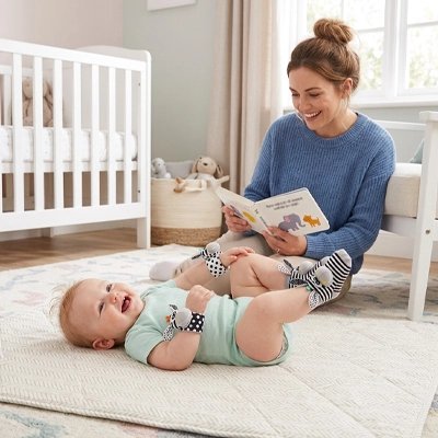 Maman lisant un livre à un bébé heureux avec un hochet bébé pour éveil sensoriel.