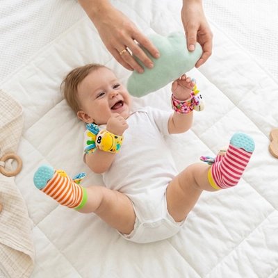 Bébé heureux jouant avec un hochet bébé coloré, éveil sensoriel sur un matelas blanc.