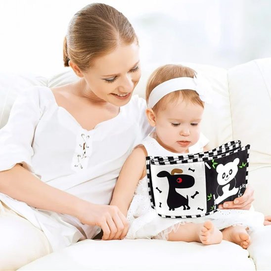 Livre en tissu bébé : une maman et son enfant découvrant un livre en tissu contrasté.