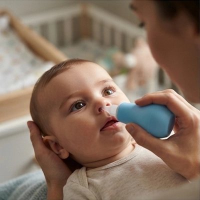Mouche bebe | Confort Douceur : parent soulageant le nez du bébé avec un mouche bébé.