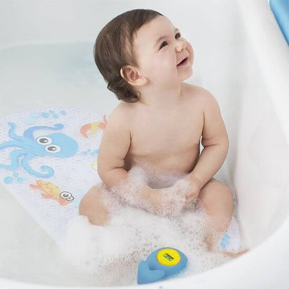 Tapis de bain bébé avec motif océan sur lequel un bébé s'amuse dans la baignoire, antidérapant et sécurisé.