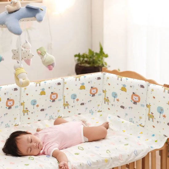 Bébé paisiblement endormi dans un lit avec un tour de lit bebe coloré et sécurisant.