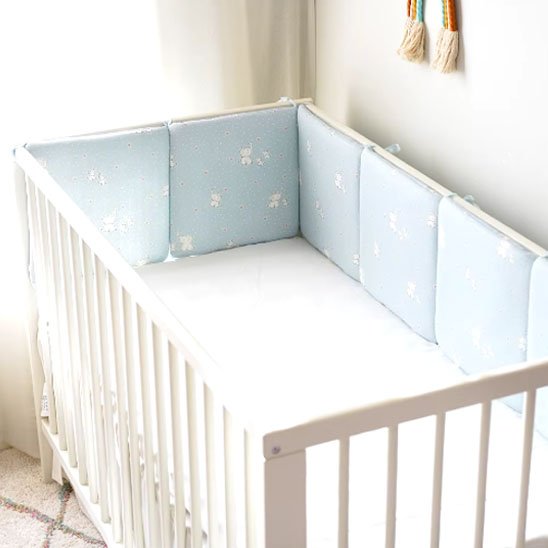 Tour de lit bebe bleu clair dans un berceau pour sécuriser le sommeil de l'enfant.